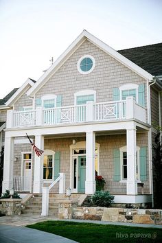 a large house with green shutters and an american flag on the front porch is shown