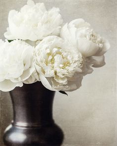 white flowers are in a black vase with the words handmade on it's side