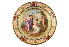 a decorative plate with an image of three women and one man on the side, painted in gold