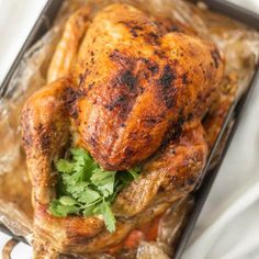 a roasted chicken with parsley in a tin foil container