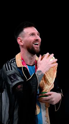 a man holding a soccer ball in his right hand and wearing a jacket with stripes on it