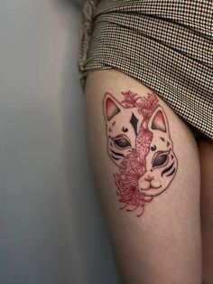 a woman's thigh with a cat tattoo on her left leg and flowers in the middle