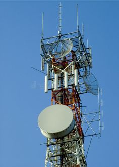 a very tall tower with many antennas on it's sides against a blue sky