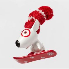 a toy dog on a snowboard with a red hat and eyeballs attached to it