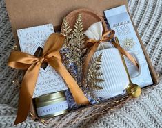 an open gift box with candles, cookies and other items in it sitting on a blanket