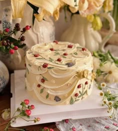 a white cake sitting on top of a table next to flowers