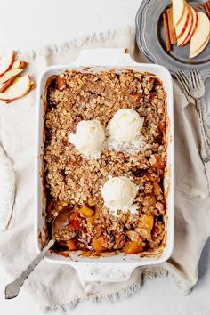 an apple crisp with ice cream in a white casserole dish on a table