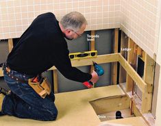 a man in black shirt working on bathroom wall