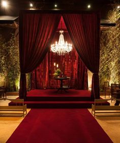 a red stage set up with chandelier and chairs