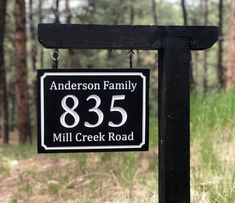 a black and white sign that says anderson family 855 mill creek road in front of some trees