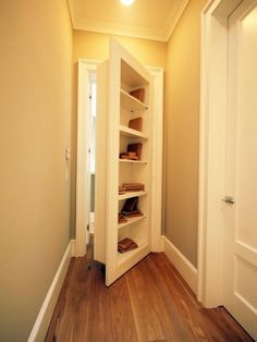 an empty hallway with white walls and wooden floors is pictured in this image, there are shelves on either side of the door