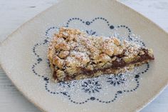 a piece of dessert on a plate with powdered sugar and chocolate toppings in the center