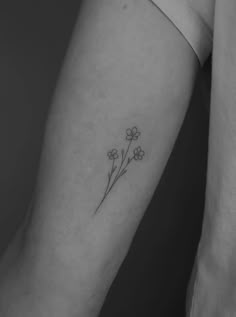 a small flower tattoo on the left inner arm and forearm, with three flowers in it