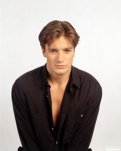 a young man posing for a photo with his shirt open and looking at the camera