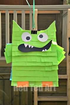 a green monster made out of construction paper hanging from a clothes line with eyes and mouth