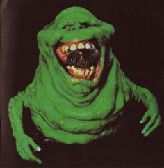 a green creature with its mouth open and teeth wide open, on a black background