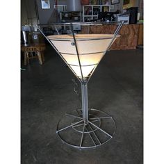 a light up martini glass sitting on top of a metal stand in a room filled with furniture