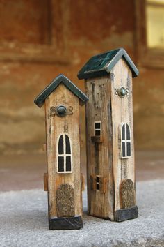 two small wooden houses sitting next to each other on the cement floor in front of a building