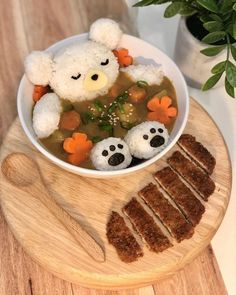 a bowl of soup with teddy bears and carrots in it on a cutting board