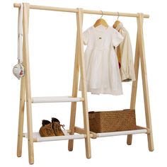 a wooden clothes rack with shoes and baby clothing hanging on the top shelf, next to a wicker basket