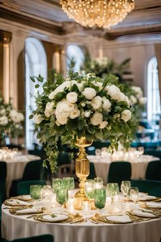 the centerpiece is surrounded by white flowers and greenery, along with green velvet chairs