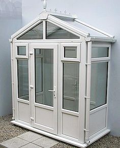 a small white building sitting on top of a tile floor next to a wall and window