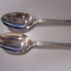 two silver spoons sitting next to each other on a table