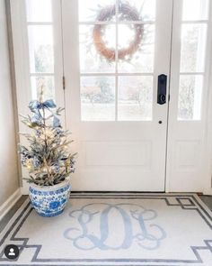 a decorated christmas tree sitting in front of a white door with a monogram on it