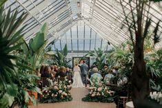 a bride and groom are walking down the aisle at their wedding ceremony in a greenhouse