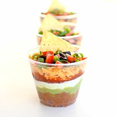 three cups filled with different types of food on top of a white tablecloth and red background