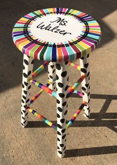 a colorful stool with the words miss uwe painted on it's top and bottom