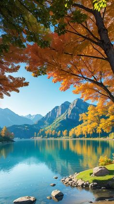 a lake surrounded by mountains and trees with autumn leaves on the water's edge