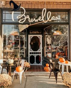 a store front with pumpkins and chairs outside