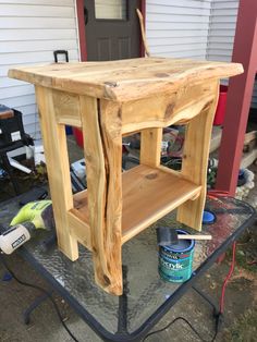 a small wooden table sitting on top of a metal stand in front of a house