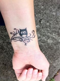 a small owl tattoo on the wrist