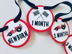 three red and white tags with cars on them that say 1 month, 2 months