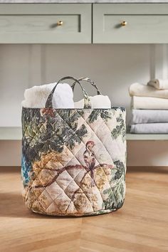 a quilted basket with towels in it on the floor