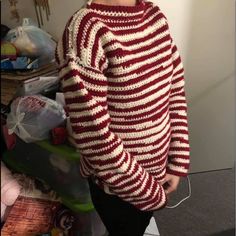 a woman wearing a red and white striped sweater standing next to a pile of plastic bags