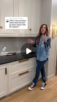 a woman standing in front of a kitchen counter with an ad on the wall behind her