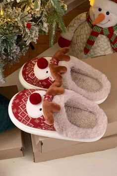 two christmas slippers with reindeer noses on them sitting in front of a snowman