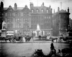 an old black and white photo of horse drawn carriages in the middle of a city