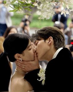 a bride and groom kissing in front of a crowd