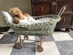 a teddy bear is sitting in a baby's stroller on the floor next to a dresser