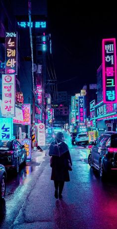 a woman with an umbrella walks down the street in front of neon signs at night