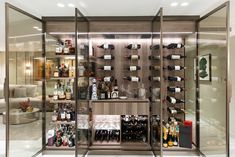 a wine cellar with glass walls and shelves filled with bottles, glasses, and other items