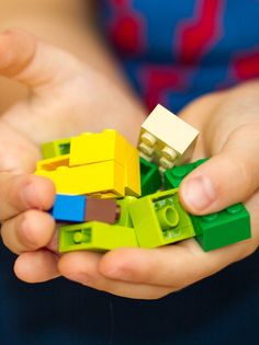 a child holding several legos in their hands