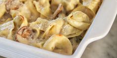 a white casserole dish filled with pasta and mushrooms