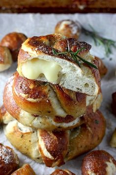 some bread rolls with cheese and herbs on top are stacked up in the shape of buns