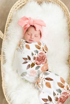 a newborn baby is sleeping in a basket wearing a pink headband and flowered blanket