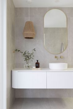 a bathroom with a sink, mirror and vase on the counter top in front of it